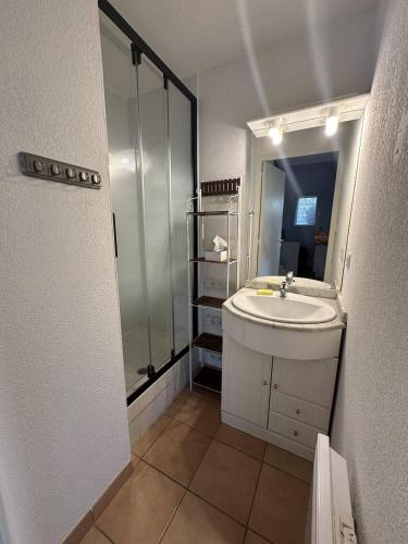 une salle de bain blanche avec un lavabo et une douche dans l'établissement G1 Manadiers T3 parking piscine terrasse, à Saintes-Maries-de-la-Mer