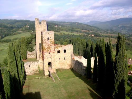 an old castle in a field with cypress trees at Appartamento Borgo Mezzo in Pratovecchio