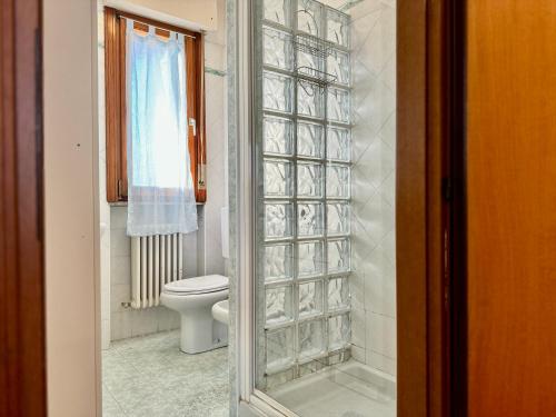 a bathroom with a toilet and a glass shower door at 82, Attico Leonardo in Lido Adriano