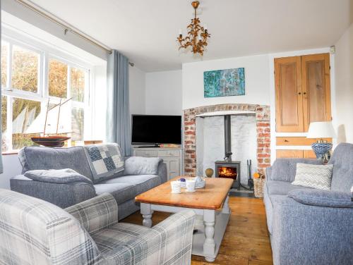 a living room with two couches and a fireplace at School House in Aberffraw