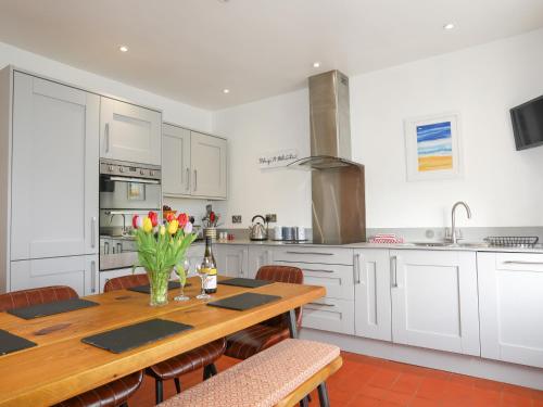 a kitchen with a wooden table with flowers on it at School House in Aberffraw