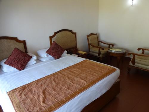 a bedroom with a large bed with two chairs at KTDC Samudra in Kovalam