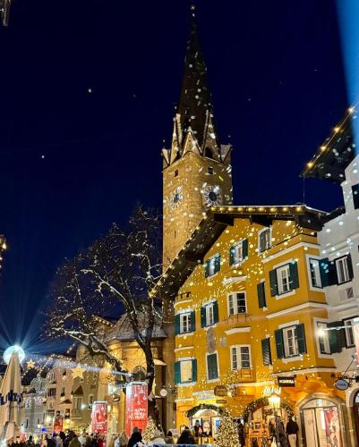 a large yellow building with a clock tower at night at TONIS cozy Guesthouse by Alpin Charme Apartments in Reith bei Kitzbühel