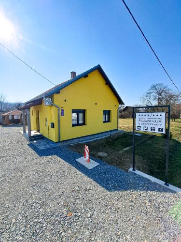 a yellow building with a sign in front of it at Studio apartmani FLAVO LUX in Donji Čaglić