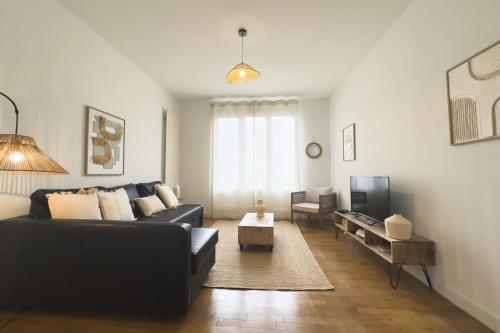 un salon avec un canapé noir et une télévision dans l'établissement #HH Le Marceau Caserne de Bonne, à Grenoble