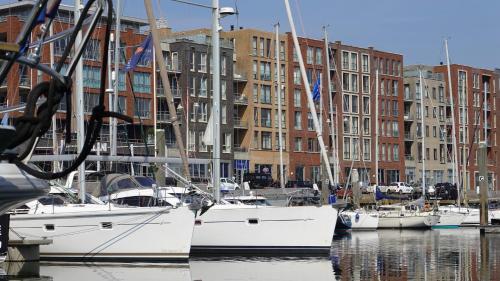 een groep boten aangemeerd in een haven met gebouwen bij BizStay Harbour III Scheveningen Apartments in Scheveningen