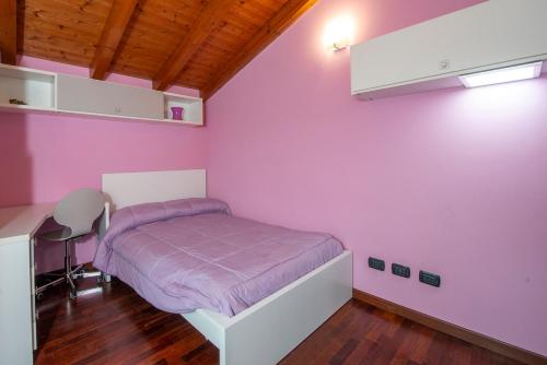 a bedroom with pink walls and a bed with purple sheets at Villa Ninfa Luxe in Arona