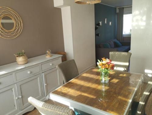une table de salle à manger avec un vase de fleurs dessus dans l'établissement le duplex de la mer, à Le Portel