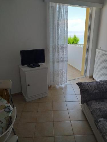 a living room with a flat screen tv on a cabinet at SereneLands Seaside House in Liyiá
