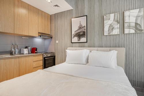 a bedroom with a white bed and a kitchen at Private Tropical Poolside Studio by Blue Cloud Holidays in Sharjah Intl