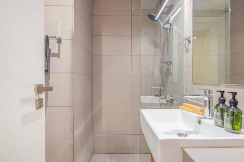 a white bathroom with a sink and a shower at Private Tropical Poolside Studio by Blue Cloud Holidays in Sharjah Intl