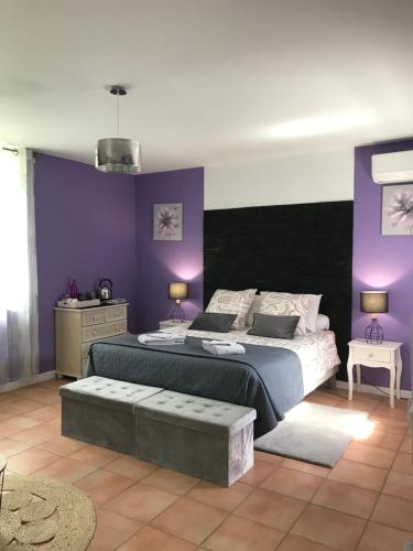 a bedroom with a large bed and purple walls at Chambre d'hôte Lavande - Le soleil des Cévennes in Saint-Jean-du-Gard