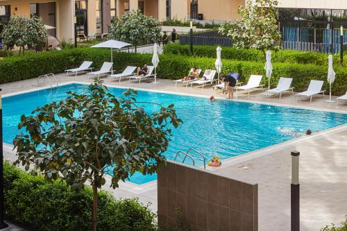 a swimming pool with chairs and people in a building at Private Tropical Poolside Studio by Blue Cloud Holidays in Sharjah Intl