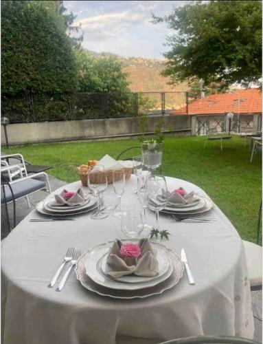 a table with a white table cloth with plates and wine glasses at Charming & Luxury Villa Como Lake in Como