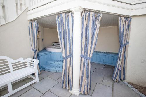 a porch with blue and white curtains and a bench at The Chanler at Cliff Walk in Newport