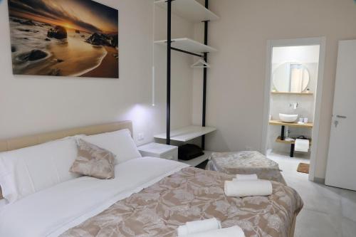 a white bedroom with a large bed and a bathroom at La Nuit in Agrigento