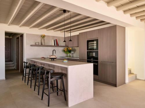 a kitchen with a large island with bar stools at Mykonos Rocks Villas & Suites in Mýkonos City