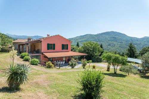 a house in a field with mountains in the background at Alba al Rifugio Arcobaleno in Popiglio