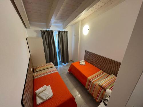 a small bedroom with an orange bed and curtains at Luciano Home in Gonnesa