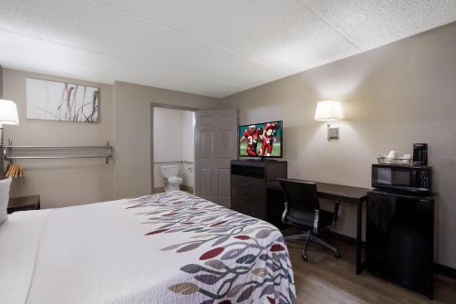 a hotel room with a bed and a desk and a tv at Red Roof Inn Atlanta Airport NE Conley in Conley