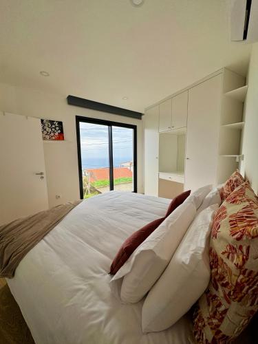 a bedroom with a large white bed with a large window at Calheta Nest in Calheta