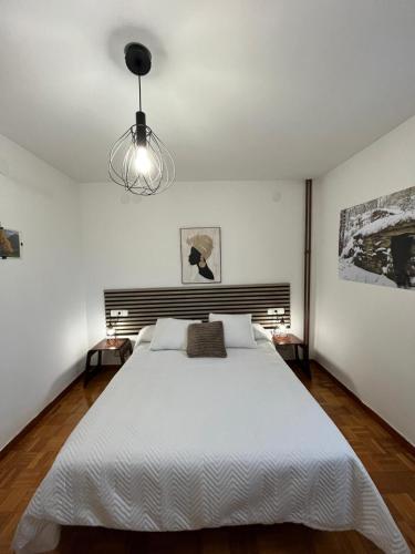 a bedroom with a large white bed and a chandelier at Dupléx en Estación de Manzaneda in Prada