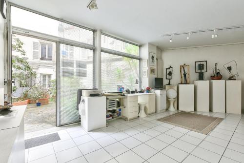 une cuisine avec des appareils blancs et une grande fenêtre dans l'établissement Atelier d’artiste, à Paris