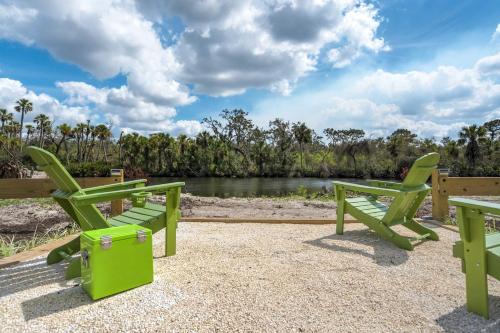 two green benches sitting next to a river at Riverside Luau Tiki Hut Fire Pit & Outdoor Fun in Bradenton