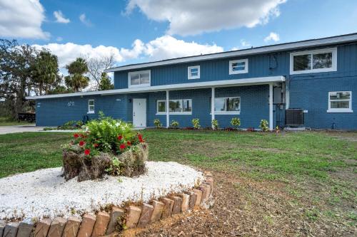a blue house with a flower bed in front of it at Riverside Luau Tiki Hut Fire Pit & Outdoor Fun in Bradenton