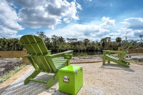 a green rocking chair and a bench next to a river at Riverside Breeze Tropical Retreat w Tiki Hut&BBQ in Bradenton