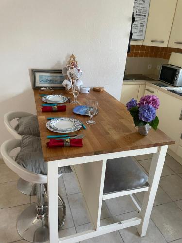 - une table en bois avec des assiettes, des verres et des fleurs dans l'établissement chambre d hôtes ALSABREIZH, à Lanvollon