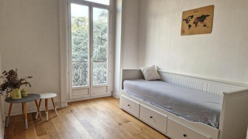 une chambre avec un lit avec une fenêtre et une table dans l'établissement Le Philippe, Appartement cosy au cœur de Lyon, 2 chambres, à Lyon