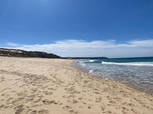 a beach with footprints in the sand and the ocean at Eco-friendly beach house in Sesimbra