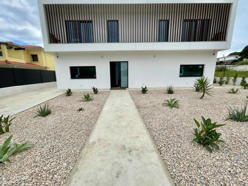 ein weißes Haus mit schwarzen Fenstern und Pflanzen in der Unterkunft Casa Iroko - a modern villa, with private pool, in a quiet area in Nadadouro