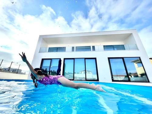 a woman laying in the water in a swimming pool at Casa Iroko - a modern villa, with private pool, in a quiet area in Nadadouro