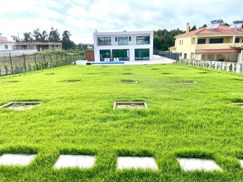 ein großer Rasenhof mit einem Haus im Hintergrund in der Unterkunft Casa Iroko - a modern villa, with private pool, in a quiet area in Nadadouro