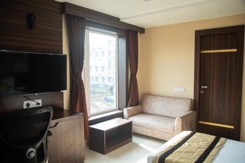 a hotel room with a tv and a chair and a window at Park Eastern Hotel in Kolkata