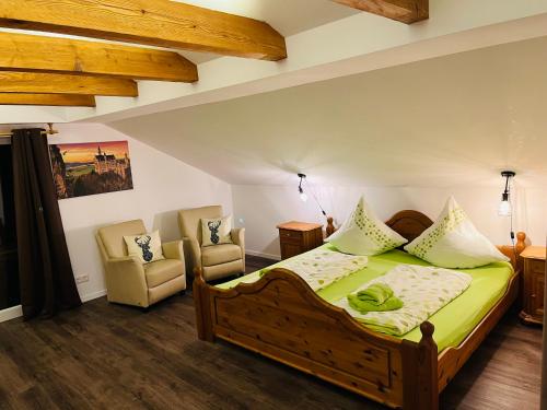 a bedroom with a wooden bed and two chairs at Landhaus „Divija Haus“ Ferienwohnung in Pfronten