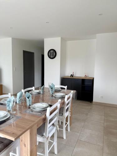 une salle à manger avec une table en bois et des chaises blanches dans l'établissement Les gîtes Pléhédelais TER, à Pléhédel