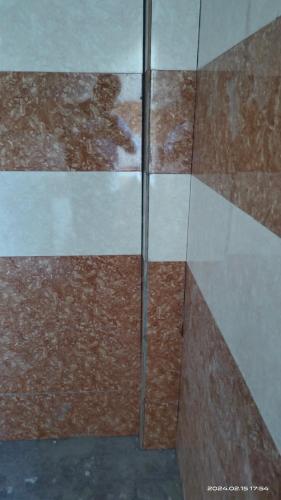 a glass shower door with brown and white tiles at VRSinn in Vishāram