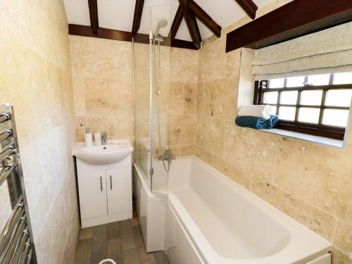 a bathroom with a bath tub and a sink at King's Cottage in Bedale