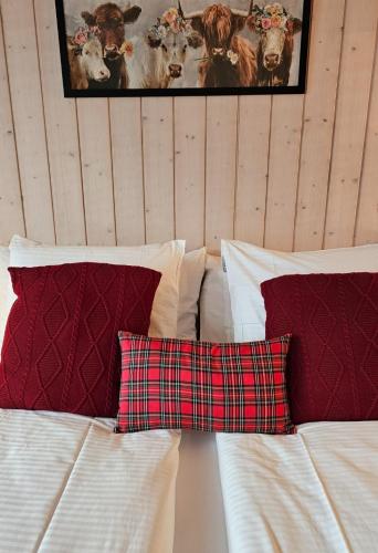 a bed with red and white pillows on it at Alpina Boutique Hotel Interlaken - Ringgenberg - Adults only ! in Ringgenberg