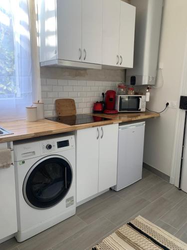 une cuisine avec un lave-linge et un micro-ondes dans l'établissement Cosy studio in Portes de Paris, aux Lilas