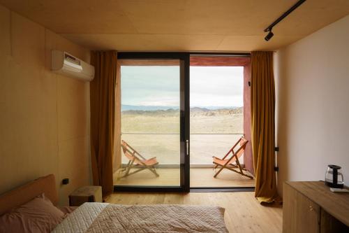 a bedroom with a bed and a window with chairs at Charyn Canyon Camp in Kökpek