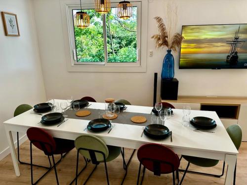 une table de salle à manger avec des chaises et une table blanche avec des verres dans l'établissement Maison Spacieuse idéalement placée bord de mer, à Pornic