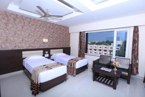 Habitación de hotel con 2 camas y ventana en Hotel Deepam, en Tiruchchirāppalli