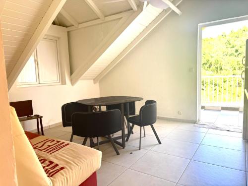 a dining room with a table and chairs and a window at Résidence Bois Jolie - Appartment Guava Jolie in Capesterre-de-Marie-Galante