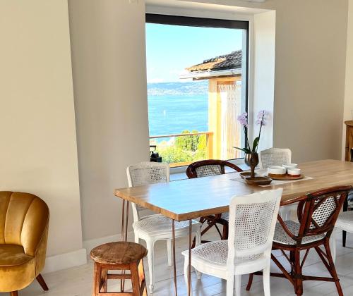 une salle à manger avec une table et des chaises et une fenêtre dans l'établissement Maison du garde barrière - Atypique et chaleureuse, à Évian-les-Bains
