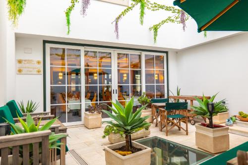 a patio with tables and chairs and potted plants at Hotel República Boutique Hotel in Tomar