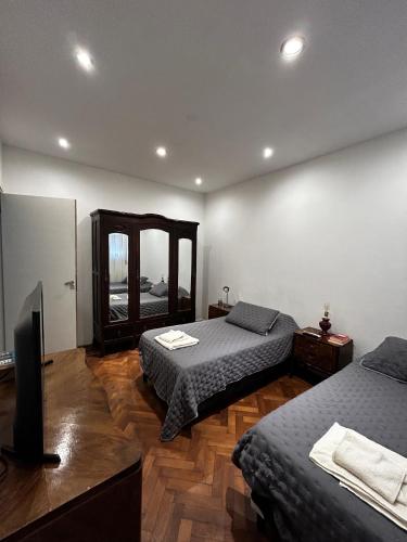 een slaapkamer met twee bedden en een spiegel bij Casa Barracas, habitación privada in Buenos Aires